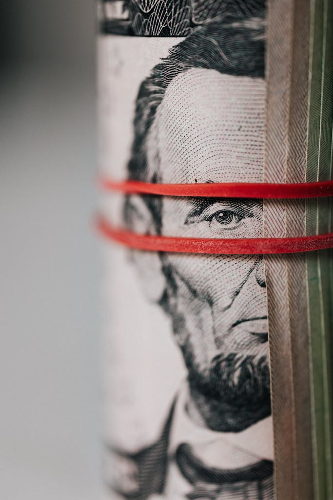 Closeup of rolled United States five dollar bills tightened with red rubber band
