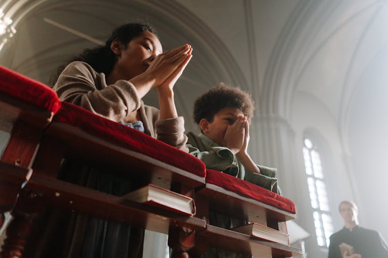 A serene moment of prayer between a mother and child inside a sunlit church.