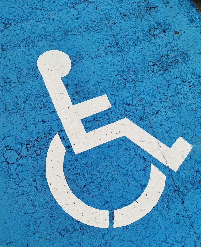 Parking space with wheelchair symbol on blue background for accessibility.