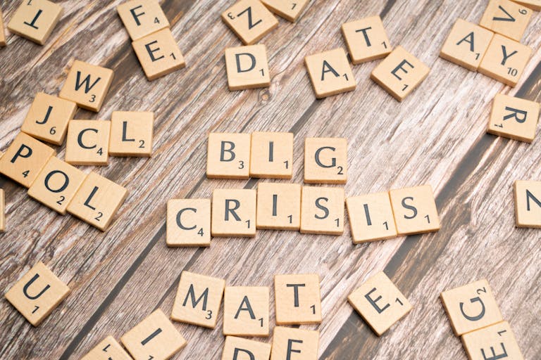 Wooden tiles forming the words 'Big Crisis' on a wooden background.