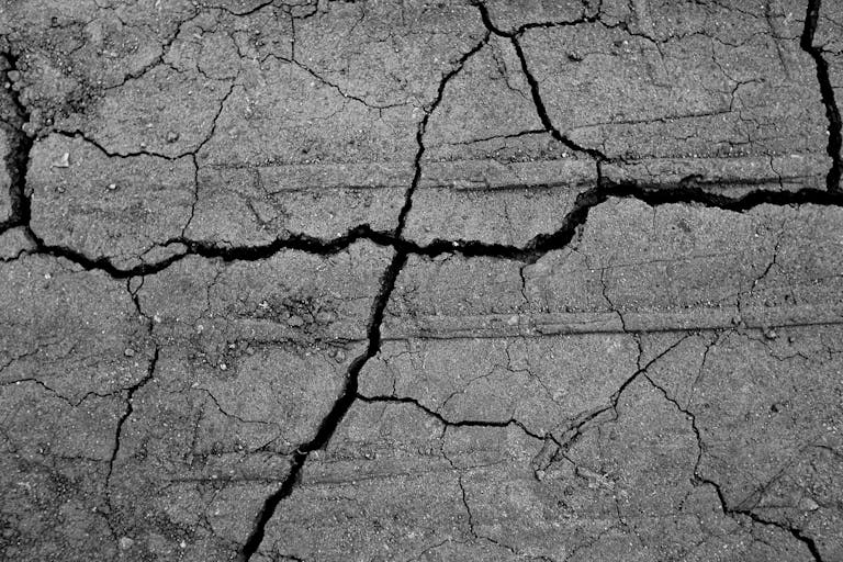 Black and white of abstract background of textured dry cracked ground in daytime